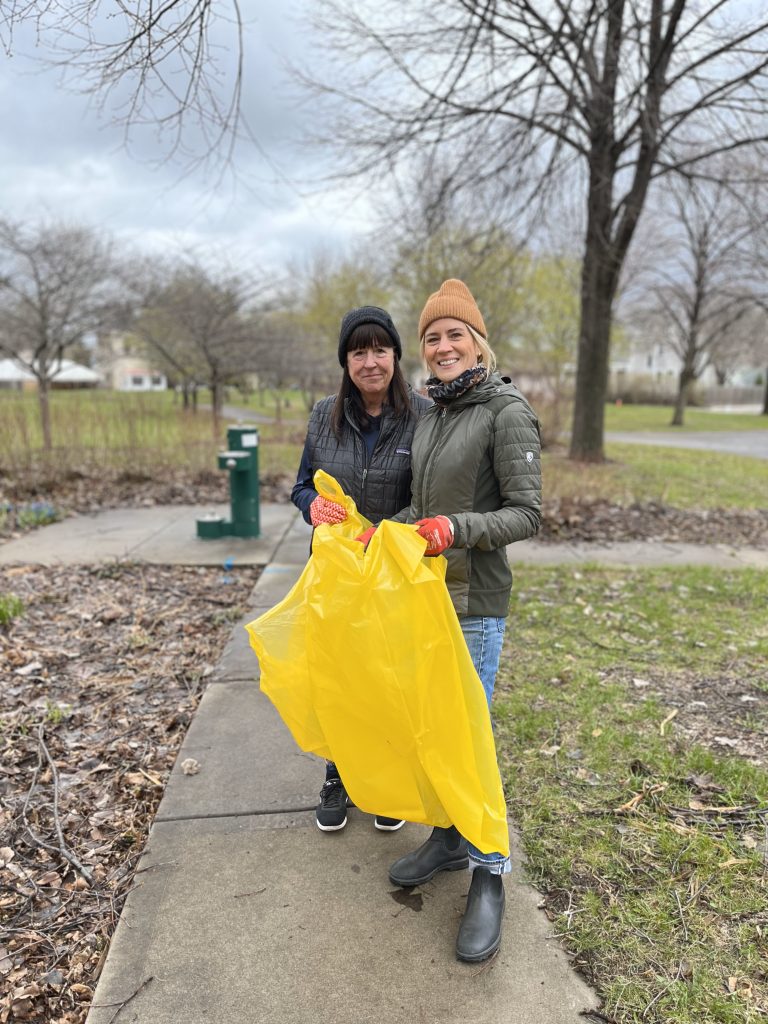 Two warmly dressed BNA Clean Sweep Volunteers holding garbage bags at Gluek Park